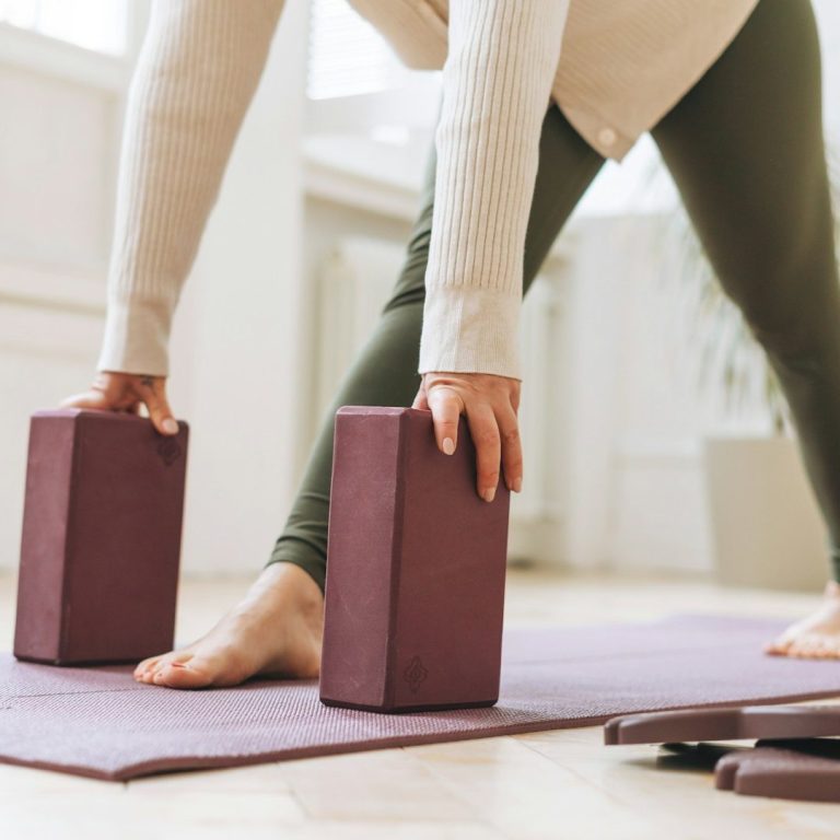 Eine Person in einer Yogapose mit zwei Blocken auf einer Matte als Hilfsmittel.
