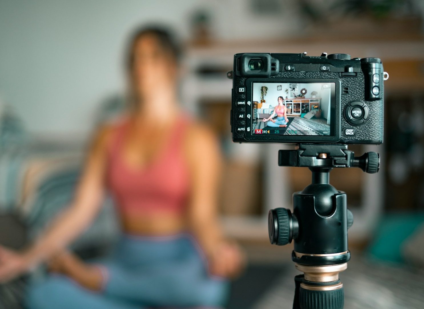Frau in Yogahaltung, gefilmt mit einer Kamera auf einem Stativ.