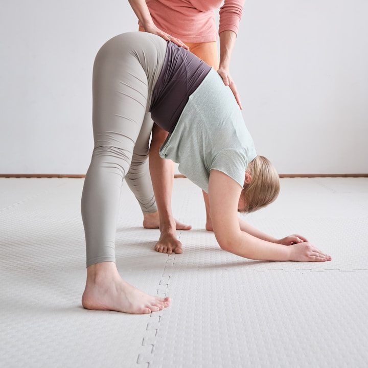 Person führt eine Yoga-Übung mit Unterstützung einer zweiten Person aus.